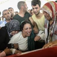 The mother of a suicide bombing victim in the Turkish border town of Suruc cries next to the coffin of her son during a funeral in Gaziantep on Tuesday. | AFP-JIJI