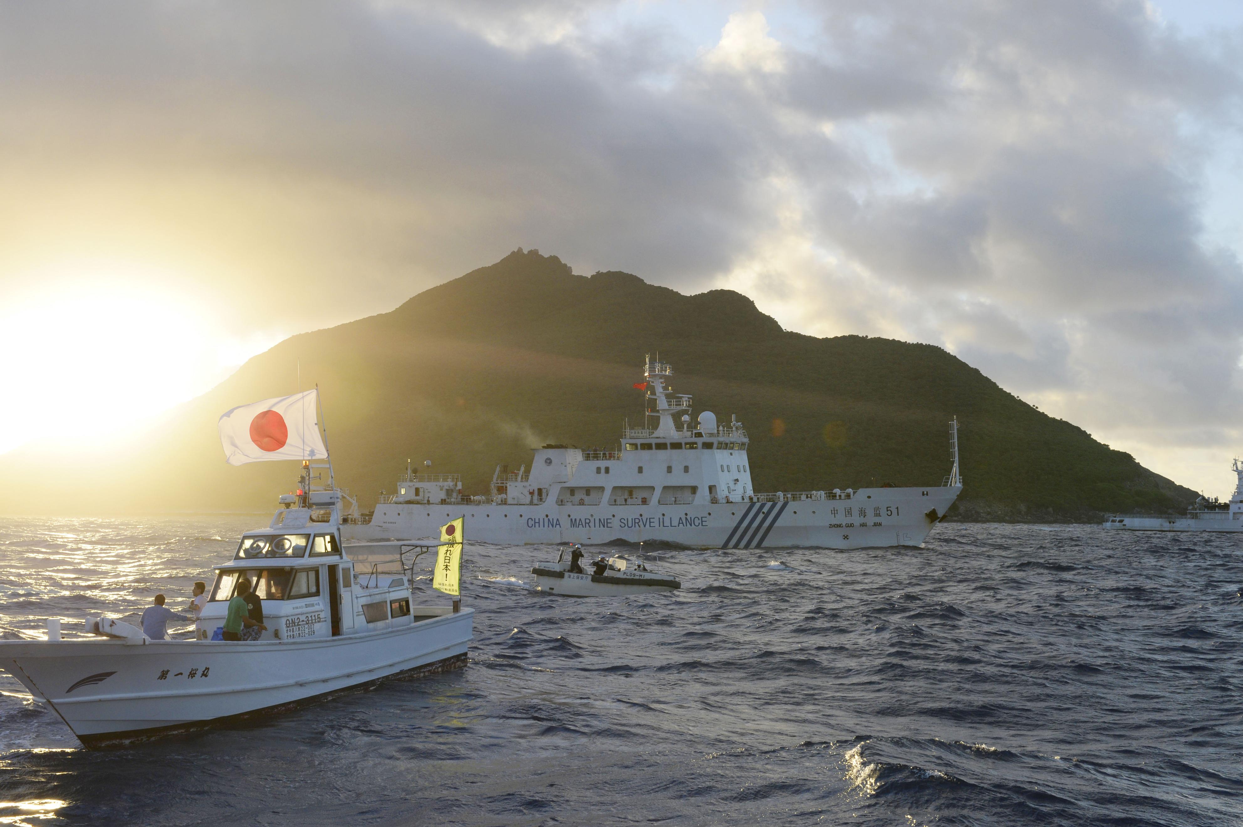 A Chinese surveillance ship cruises past a Japanese fishing boat chartered by a political group near the Senkaku Islands in July 2013. | KYODO
