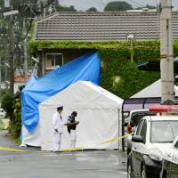 Two investigators Monday morning stand in front of an apartment complex in Yawatahama, Ehime Prefecture, where multiple bodies of babies were found. | KYODO