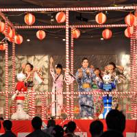 Enka singer Yuki Tokunaga (third from left) takes the stage with other performers and SoftBank Pepper humanoid robots Friday evening at a summer festival in Tokyo\'s Shibuya district. | YOSHIAKI MIURA