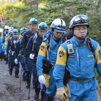 An advance team of Nagano police officers and firefighters enters the Mount Ontake area from the Nagano Prefecture side on Sunday ahead of resuming the search for bodies later this month that remain buried following the volcano\'s deadly eruption last September. | KYODO