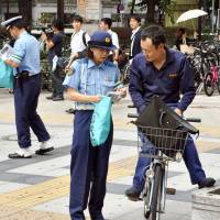 A police officer speaks to a man on a bicycle at an intersection in the city of Osaka Monday. | KYODO