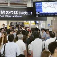 Passengers check a monitor for train delay information at JR Osaka Station on Saturday after heavy rainfall caused by a typhoon wreaked havoc in the area. | KYODO