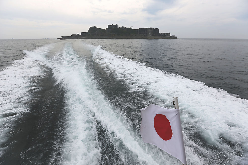 A tour boat departs June 29 from Hashima Island, commonly known as Gunkanjima ('Battleship Island'), off the city of Nagasaki. The island is one of 23 old industrial facilities that gained UNESCO recognition as world heritage 'Sites of Japan's Meiji Industrial Revolution,' meant to illustrate Japan's rapid transformation from a feudal farming society into an industrial power at the end of the 19th century. | AP