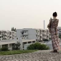 Family ties: A woman holds a baby while she looks out onto a residential area in Tokyo. Raising Japan\'s birthrate will require more creative ideas. | BLOOMBERG