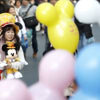 House of the mouse: A fan walks through Tokyo Disneyland, which, along with Tokyo Disney Sea, drew 31.3 million visitors in 2014, wiping the floor with its nearest domestic rival, Universal Studios Japan in Osaka. | BLOOMBERG