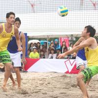 Sho Sagawa of the Sakai Blazers sets the ball as Yusuke Ishijima looks on during the V-League Summer Festival on Sunday at Odaiba beach. | KAZ NAGATSUKA