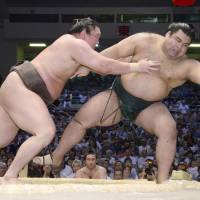 Yokozuna Hakuho (left) forces Takayasu out of the raised ring on Monday at the Nagoya Grand Sumo Tournament. | KYODO