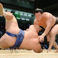 Yokozuna Hakuho manhandles Kotoshogiku during their bout on Thursday. | KYODO
