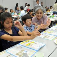 Arisa Asai, 9, and her brother, Toni, 7, stare at their forefingers while their grandmother, Motoko, watches as they take part in a test to determine which of their eyes is the dominant one. The residents of Tokyo\'s Ota Ward were among 25 children and their adult relatives who participated in drugmaker Bayer Yakuhin Ltd.\'s \"Science of Eyes\" seminar, which is aimed at providing children with material for their school summer projects, in the Roppongi district on Friday. | YOSHIAKI MIURA
