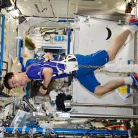 Japanese astronaut Kimiya Yui jogs while tethered to a treadmill by a spring-loaded harness in the weightlessness of orbit, in a photo he tweeted from the International Space Station on Wednesday. | KYODO