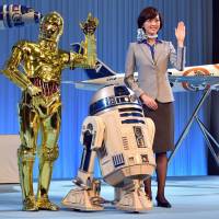 Star Wars droids C-3PO and R2-D2 pose with All Nippon Airways flight attendants as they unveil scale models of ANA Boeing 787-9 and 777-300ER aircraft in the livery of Star Wars droid characters at a news conference in Tokyo on Tuesday. ANA\'s R2-D2 jetliner will be launched for overseas air routes in October while the BB-8 jet plane will be launched for the North American air route next year.     | AFP-JIJI