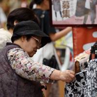 Customers look at clothes on sale at a Fukuoka shopping arcade in July. The Bank of Japan refrained Friday from expanding monetary stimulus after the central bank\'s governor voiced optimism the economy will pick up. | BLOOMBERG