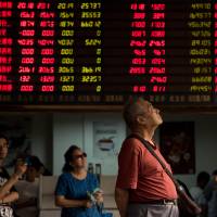 Investors monitor stock market movements at a brokerage house in Shanghai last week. Bank of Japan policymakers are increasingly worried about the impact of the Chinese yuan\'s moves on the Japanese economy. | AFP-JIJI