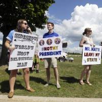 Democratic supporters (from left) Hayley Alderman, Sam McNerney and Julie Haefner stand outside the Birch Run Expo Center before Republican presidential candidate Donald Trump was scheduled to address a GOP fundraising event, Tuesday, in Birch Run, Michigan. Trump said Tuesday that China\'s devaluatioin of the yuan will \"devastate\" the U.S. | AP