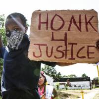 A boy holds a sign in St. Louis on Thursday. A medical examiner\'s report released Friday on a black teenager shot and killed by white St. Louis police officers appeared to contradict the police account of the shooting. | REUTERS