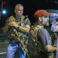 Members of the \"Oath Keepers\" walk with their weapons on a street in Ferguson, Missouri, early Tuesday. | REUTERS