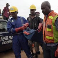 Officials of the National Emergency Management Agency (NEMA) and the paramilitary Nigeria Security and Civil Defence corps (NSCDC) carry the body of a dead passenger from a helicopter operated by the US-based Bristow Group that crashed into a lagoon at the Oworonshoki district of Lagos on Wednesday. | AFP-JIJI