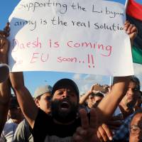 A man holds a sign during a demonstration to show support for the Libyan army under the leadership of General Khalifa Haftar, in Benghazi on Friday. The sign warns that Islamic State terrorists are coming to the EU soon. Firefights rages in varous Libyan cities Friday as Islamic State forces fought Islamic rivals and government fighters. | REUTERS