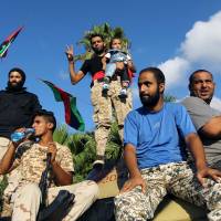Libyan supporters and troops loyal to Khalifa Haftar, a retired general and former chief of staff for Moammer Gadhafi, sit on an amored personnel carrier (APC) during a demonstration calling on the international community to arm the Libyan army on Friday in the eastern Libyan city of Benghazi. The Tobruk-based government (recognized by the international community) said in a statement that world powers were using \"double standards\" by fighting Islamic State in Syria and Iraq and \"turning a blind eye\" to the presence of the jihadis in Libya. | AFP-JIJI