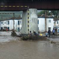 Residents attempt to clear flood debris from under a bridge in the city of Rajin, in North Korea, in this picture taken Saturday by a recent visitor. | REUTERS