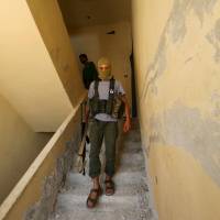 A Nusra Front fighter walks inside a building in the Sheikh Maksoud neighborhood of Aleppo, Syria, Monday. It was reported Tuesday that Nusra Front attackers captured five U.S.-trained Syrian rebels. | REUTERS