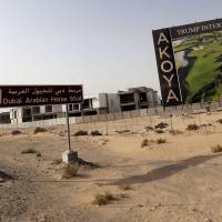 U.S. real-estate magnate Donald Trump is seen playing golf on a billboard at the Trump International Golf Club Dubai in the United Arab Emirates on Wednesday. The empire of White House hopeful Trump outside the United States extends to 12 countries, including Turkey, South Korea, India, Brazil and the United Arab Emirates. A frequent China-basher, data show Trump is off the mark in saying Beijing has continuously devalued the yuan. | AFP-JIJI