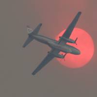 A fire-retardant airplane passes in front of the sun turned orange with smoke as a wildfire burns near Twisp, Washington, Wednesday, a day when three firefighters died battling the blaze. | AP