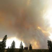 An approaching wildfire looms over a home near Twisp, Washington, Wednesday. Authorities on Wednesday afternoon urged people in the north-central Washington town to evacuate because of the fast-moving wildfire. | AP