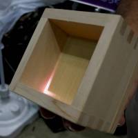 A representative of Gifu-based Ohashi Ryoki Co. shows a custom-made wooden masu cup at Maker Faire Tokyo 2015. Thanks to tech concealed in its base, the cup glows when tilted. | KAZUAKI NAGATA