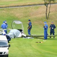 Investigators inspect an ultra-light plane that crashed into a golf course earlier on Sunday in Tsukuba, Ibaraki Prefecture. | KYODO