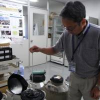 Noriyoshi Ichikawa, director of the Preservation and Research Center in Yokohama, pulls up tubes of frozen reproductive cells from a tank. | MIZUHO AOKI