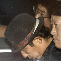 Koji Yamada (center), who was arrested on suspicion of abandoning the body of a 13-year-old girl found murdered in Osaka Prefecture last week, is escorted into the Osaka Prefectural Police headquarters on Friday night. | KYODO