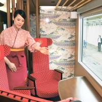 An attendant shows off a seat inside the Hanayome Noren (Bride Curtain), West Japan Railway Co.’s tourist train decorated inside and out with motifs representing local traditional crafts such as Wajima lacquerware and Kaga kimono dyeing techniques after it was unveiled in Hakusan, Ishikawa Prefecture, on Friday. | KYODO