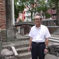 Shigeyuki Anan poses on July 29 in front of bricks that used to be part of Urakami Cathedral in the city of Nagasaki, which was ruined by the \"Fat Man\" plutonium bomb 70 years ago. | TOMOKO OTAKE