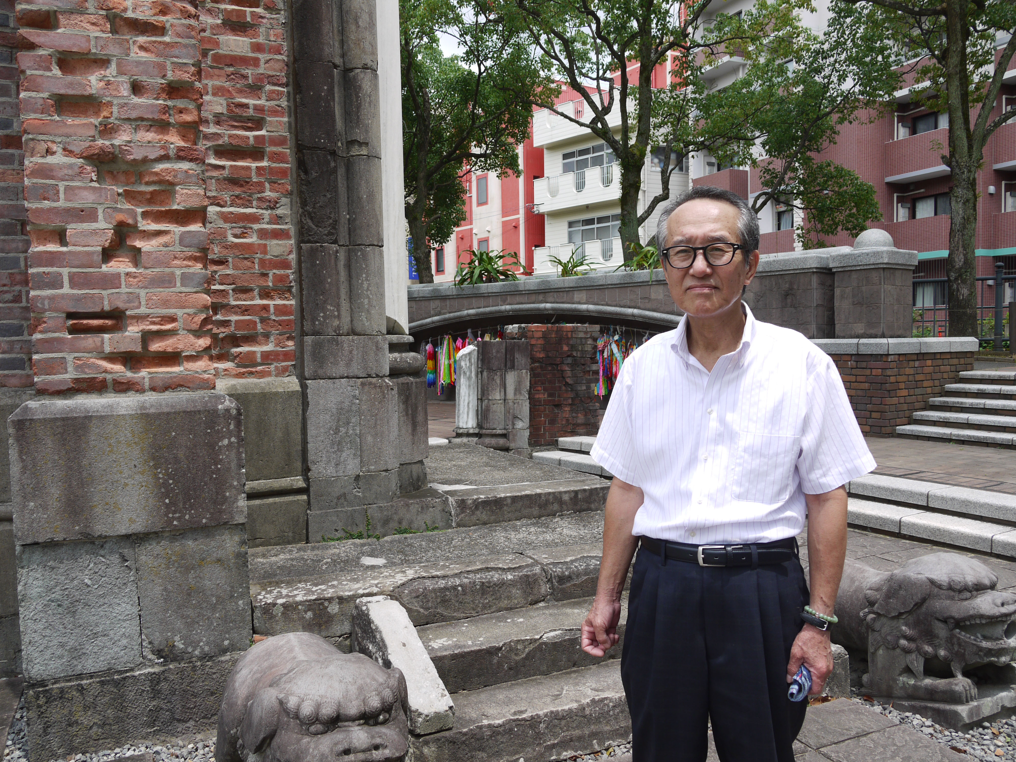 Shigeyuki Anan poses on July 29 in front of bricks that used to be part of Urakami Cathedral in the city of Nagasaki, which was ruined by the 'Fat Man' plutonium bomb 70 years ago. | TOMOKO OTAKE