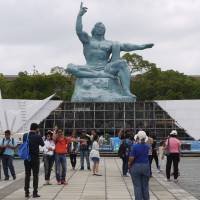 Tourists stop to take photos in front of the Peace Statue at the Nagasaki Peace Park on July 29. | TOMOKO OTAKE
