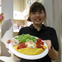 A waitress shows off a \"Sailor Moon\" meal at Anion Station in Shinjuku Ward, Tokyo, on Monday. | KAZUAKI NAGATA