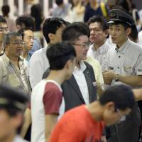 An official at JR Tachikawa Station explains to passengers the suspension of train services following a cable fire on Tuesday night. | KYODO