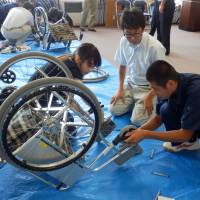 High school students try their hand at restoring a corroded wheelchair destined for Sri Lanka during a seminar held in Daisen, Akita Prefecture, on Aug. 7. | MAGDALENA OSUMI