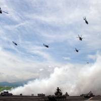 Defenders: Ground Self-Defense Forces helicopters fly over armored vehicles during an annual live-fire exercise at the Higashi-Fuji firing range in Gotenba, Shizuoka Prefecture. | AFP-JIJI