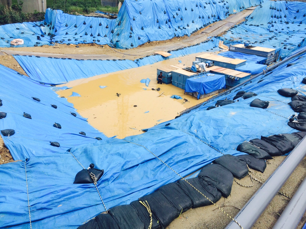 Dirty secret: Japanese workers toil without safety gear at the flooded U.S. military dioxin dump site in Okinawa City on Sunday. The land used to be part of Kadena Air Base, the Pentagon's busiest Okinawa installation during the Vietnam War. | KEN NAKAMURA-HUBER