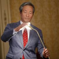 FIFA presidential candidate Chung Mong-joon adjusts a lamp during a press conference in Paris on Monday. | AP