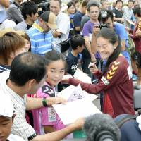 Nadeshiko Japan soccer star Homare Sawa (far right) signs messages of congratulations for fans in Kobe on Wednesday, a day after she announced her marriage. | KYODO