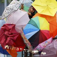 A pro-democracy protester fixes an installation made of umbrellas, symbols of the protest, in Hong Kong\'s financial central district last October. | REUTERS