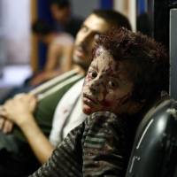 A Syrian boy waits to receive treatment at a makeshift hospital following reported airstrikes by government forces in the rebel-held area of Douma, east of Damascus, on Sept. 19. | AFP-JIJI