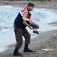 A Turkish gendarmerie carries a young migrant who drowned in a failed attempt to sail to the Greek island of Kos, in the coastal town of Bodrum, Turkey, Wednesday. At least 11 migrants believed to be Syrians drowned as two boats sank after leaving southwest Turkey for the Greek island of Kos, Turkey\'s Dogan news agency reported on Wednesday. | DHA / NILUFER DEMIR / REUTERS