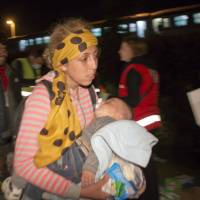 Migrants and refugees walk toward Hungary after arriving by train in Botovo, Croatia, on the Hungarian border, Tuesday. At a contentious meeting, European Union ministers agreed Tuesday to relocate 120,000 refugees among the bloc to ease the strains on front-line nations like Greece and Italy, which are being overwhelmed by the continent\'s ballooning migrant crisis. | AP