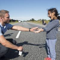 A Danish policeman plays with a refugee girl north of Padborg on Sept. 9. | REUTERS