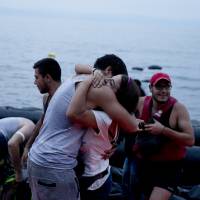 Syrian refugees react as they arrive on the shores of the Greek island of Lesbos after crossing the Aegean Sea from Turkey on a inflatable dinghy Tuesday. | AP